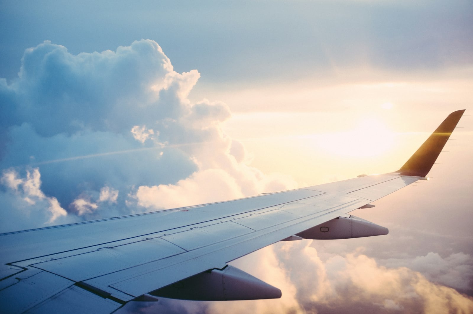 Airplane wing above clouds at sunset